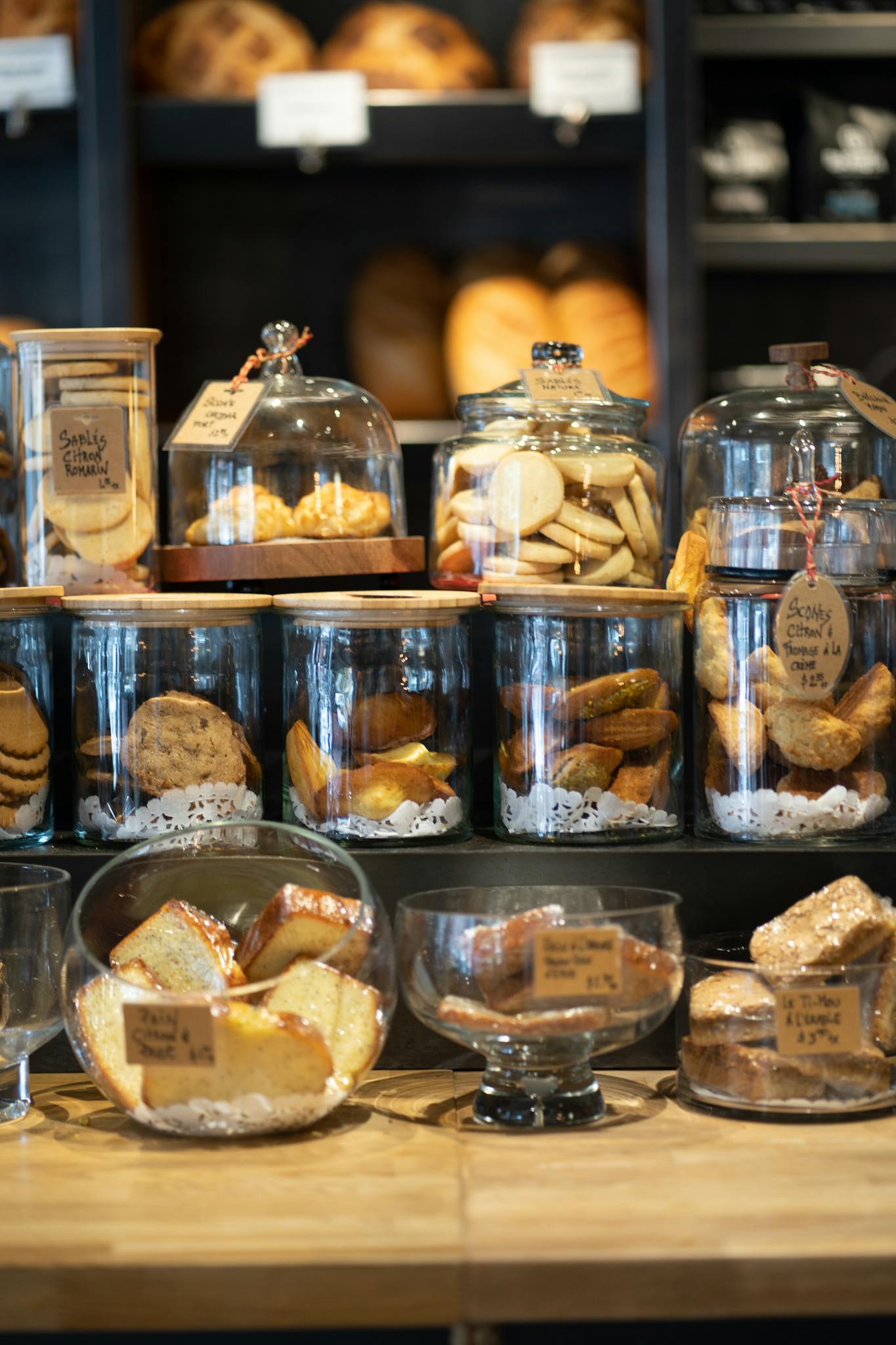 A variety of cookies and pastries artfully displayed in glass jars within a cozy bakery setting.