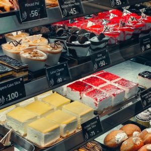 Delicious assortment of pastries and cakes displayed in a bakery with price tags.